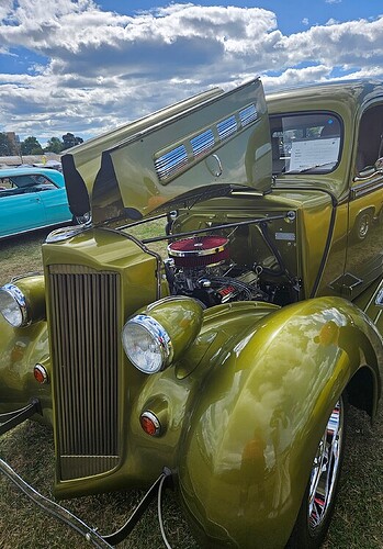 An antique car with the hood lifted to show the engine.