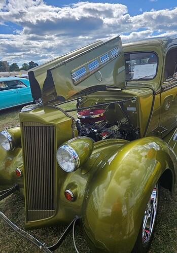 An antique car with the hood lifted to show the engine.