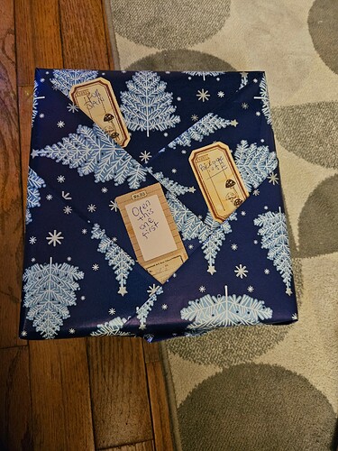 A gift wrapped in dark blue wrapping paper patterened with white and light blue Christmas trees.